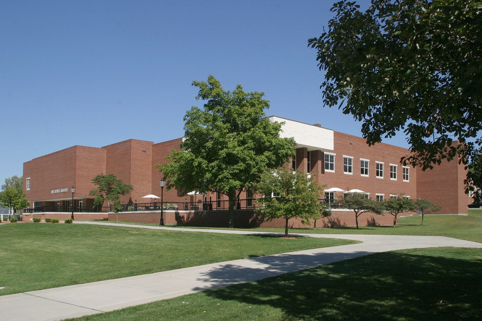 A modern brick college building across a sunny lawn