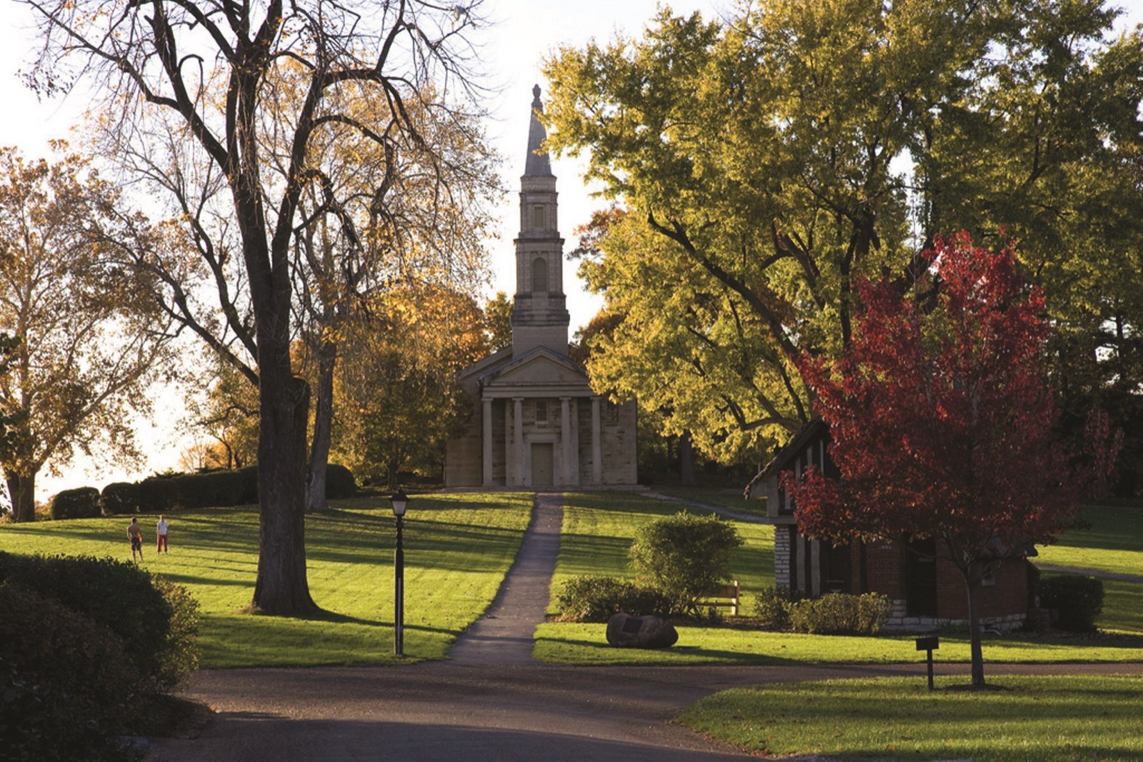 A white chapel spire among autumn trees